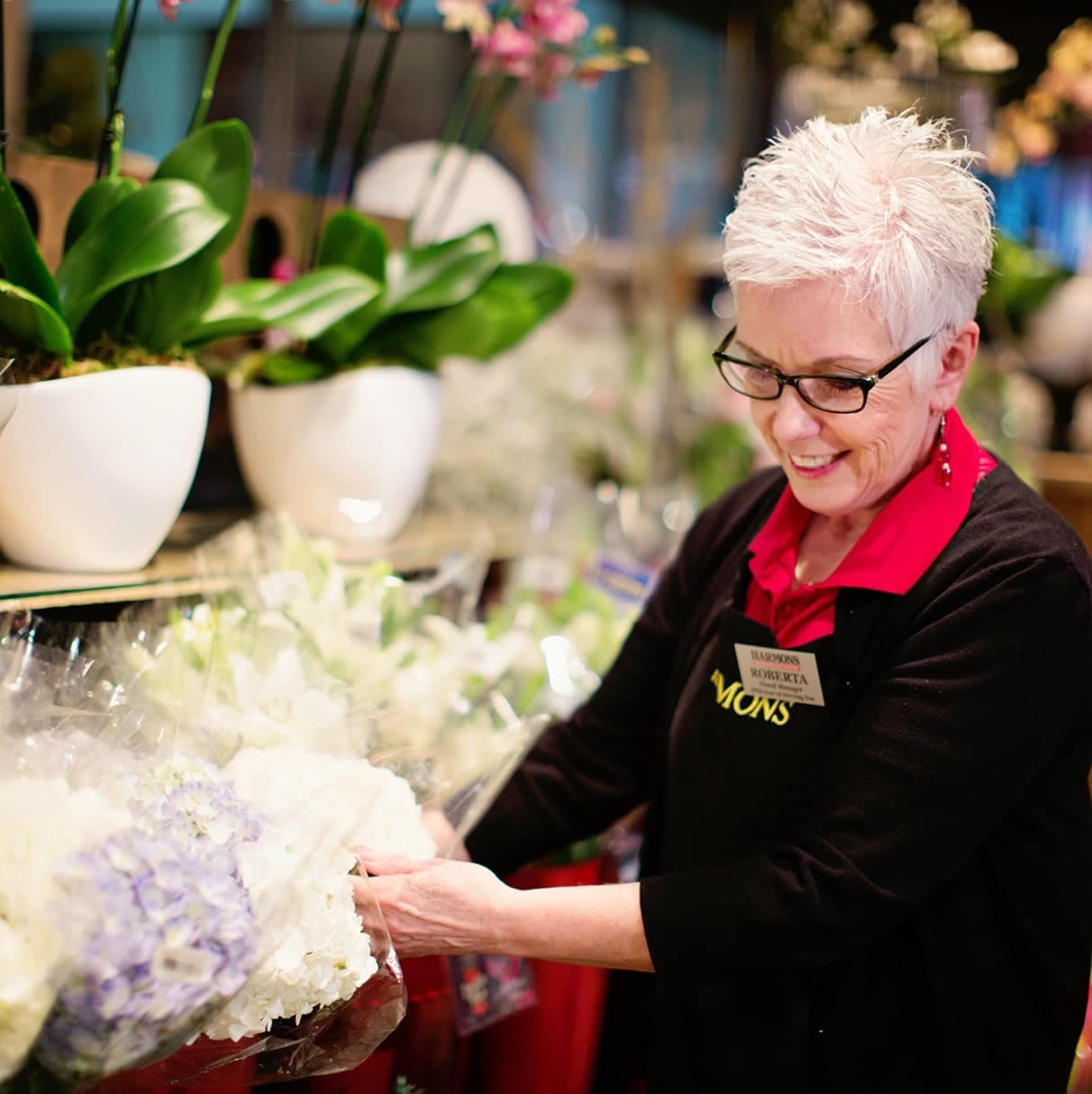 A Harmons florist arranging a bouquet of white flowers