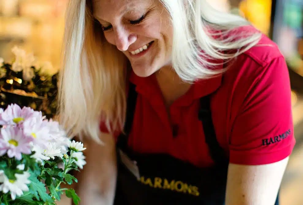 A Harmons floral designer smiling among fresh flower arrangements