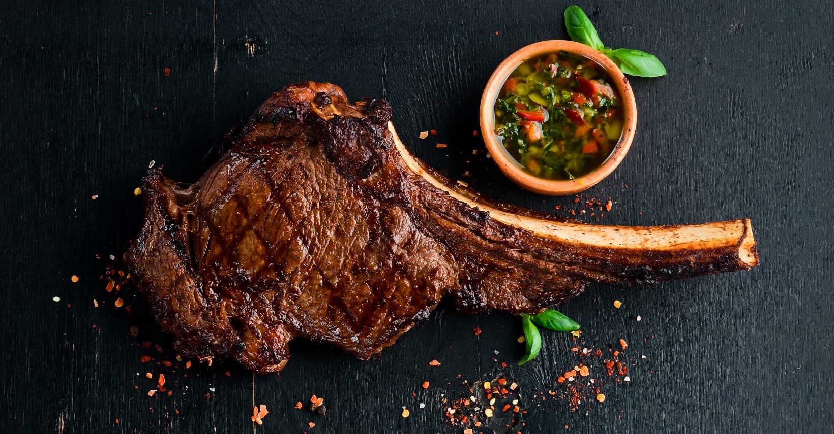 Grilled tomahawk steak with a side of chimichurri sauce