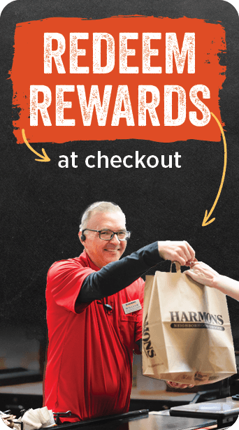 Redeem rewards at checkout — a Harmons associate handing a bagged order across the checkstand